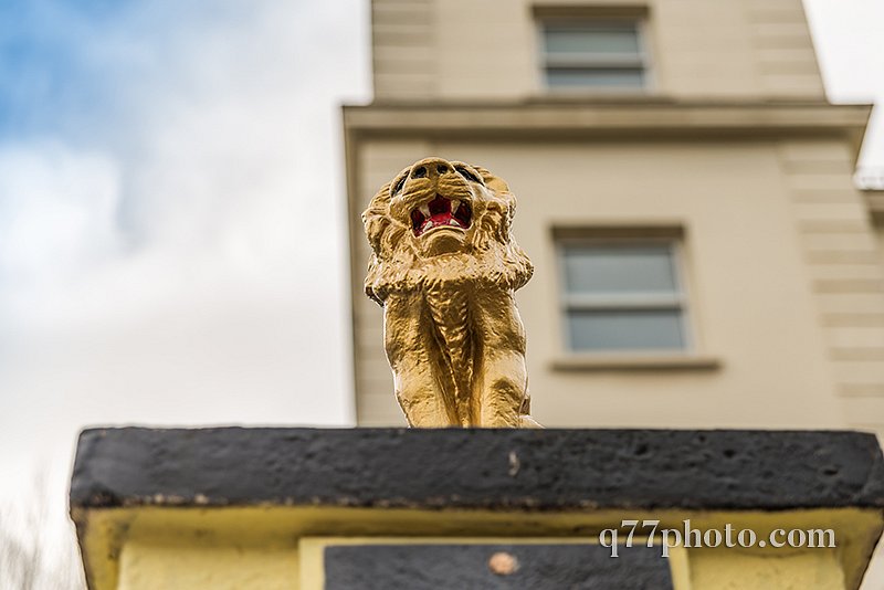 view from below on a gold lion on a pedestal in front of the gat