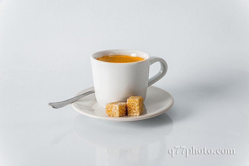 Black coffee in white cup, brown sugar cubes on saucer