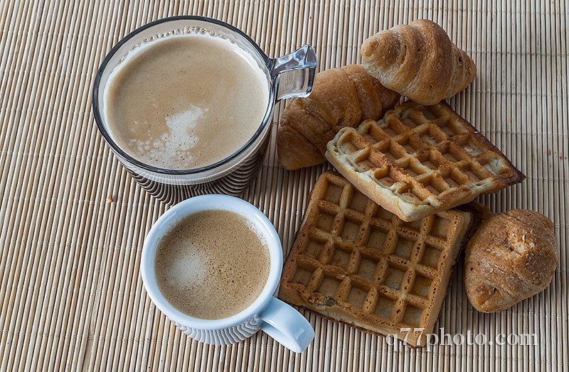 Fresh croissants and delicious waffles with two coffee on bamboo
