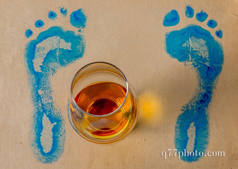 The glass of single malt whiskey, gray paper with blue footprint