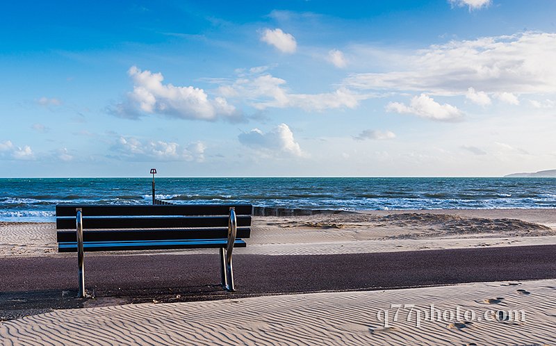 Beautiful seaside view, sandy beach, bench, blue sky, ocean and 