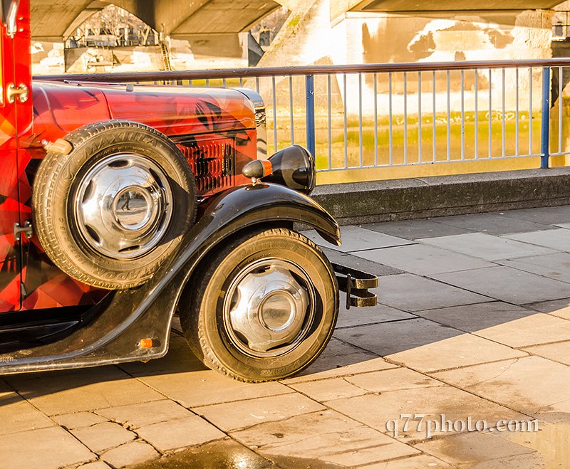 front of the old style car on the banks of the river