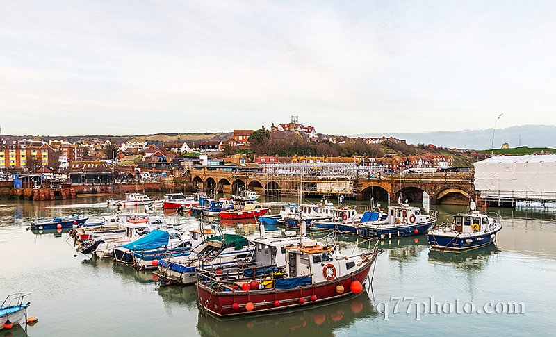 Boats and ships moored in a small port, in the background stone 