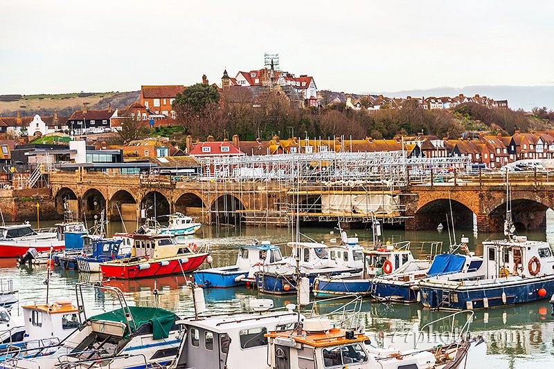 Boats and ships moored in a small port, in the background stone 