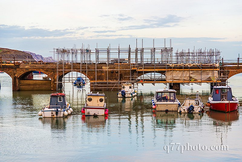 Boats and ships moored in a small port, in the background stone 