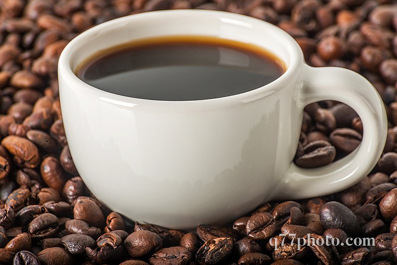 Black coffee in white cup, against a background of brown coffee 