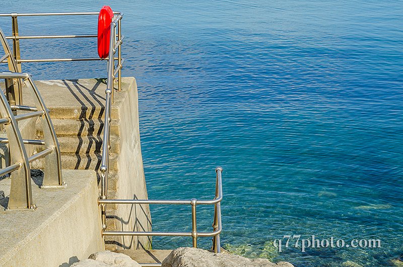 Beautiful blue ocean, part of the promenade with lifebuoy, sunny